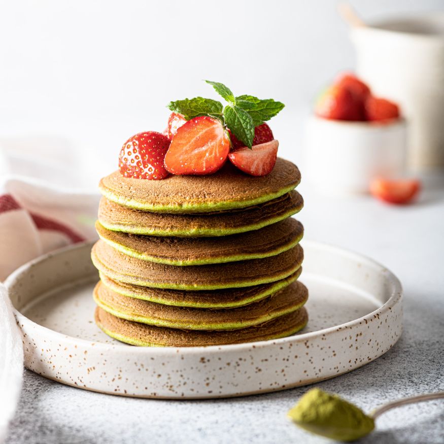 Pancakes garniert mit Erdbeeren und verfeinert mit Matcha-Grünteepulver.